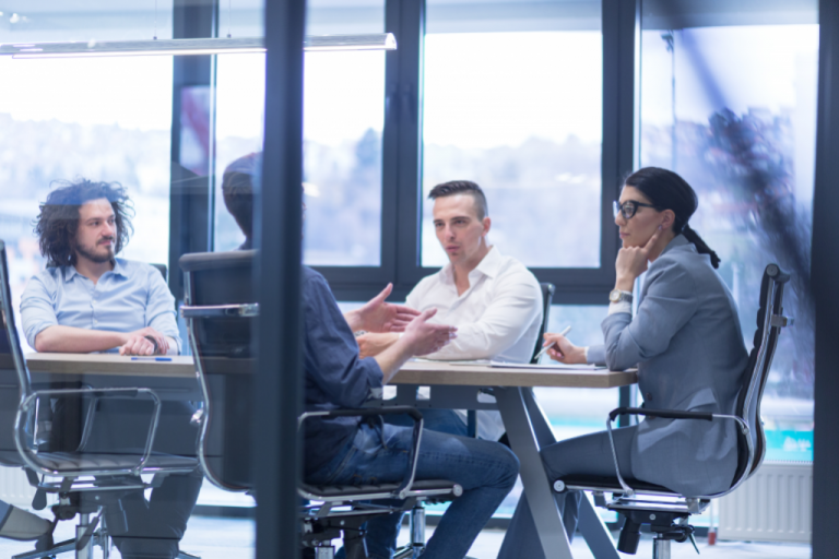 Business meeting in a modern office with four colleagues discussing around a table