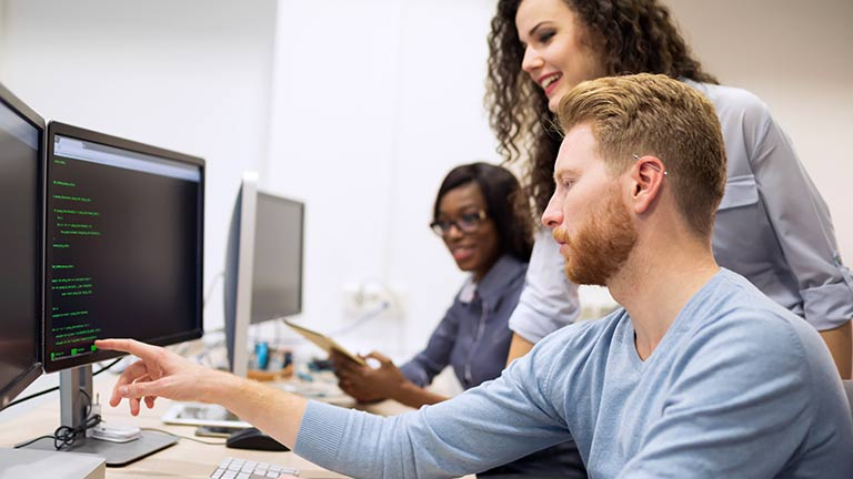 Colleagues in the office discussing data shown on the computer.