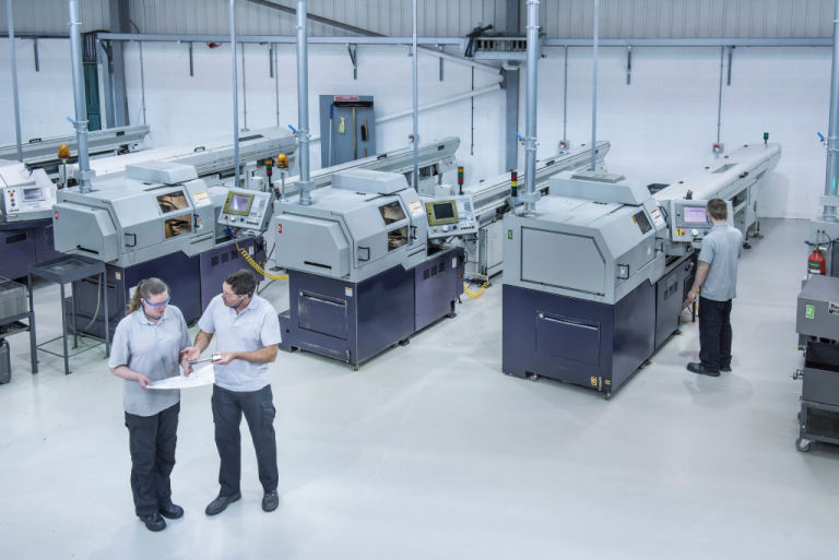 Workers in a modern manufacturing facility operating and inspecting CNC machines